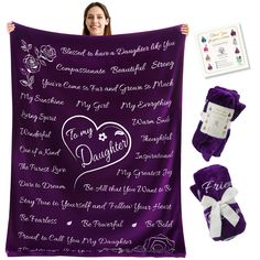 a woman holding up a purple blanket with white writing on it and two matching items