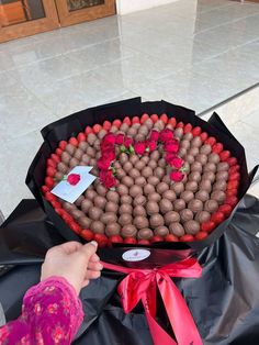 a person holding a bouquet of flowers with chocolates in the shape of a heart