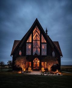 a large house lit up at night with lights on the windows and trees in front