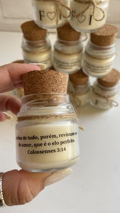 a hand holding a small jar filled with some kind of substance next to other jars