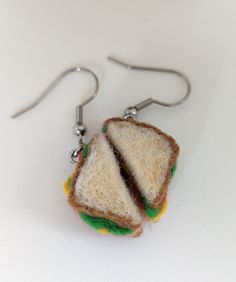 a pair of earrings made to look like a sandwich is hanging from hooks on a white surface