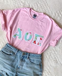 These classic and vintage-style letters are perfect for new and seasoned sorority women alike! Features double-stitched rose letters with white polka dots on aqua fabric on a white outline attached to a comfortable unisex baby-pink tee. This seller is licensed with Affinity Licensing to ensure a verified, quality product. Care Instructions: Machine wash cold, inside out; Tumble dry low; Low iron as needed Sorority Block Letters Shirts, Sorority Letter Shirt, Cute Sorority Shirts, Sorority Letter Shirts, Sorority Shirts Letters, Sorority Clothes, Rainbow Confetti, Sorority Events, Sorority Merch