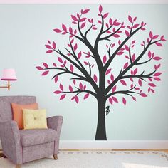 a living room with a chair and tree wall decal