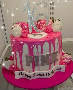 a pink birthday cake with white frosting and decorations on the top that says happy sweet 16