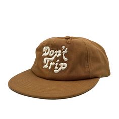 On a white background is a brown unstructured 6 panel baseball hat with white embroidery that reads, Don't Trip. Strapback Hats, Beach Days, Custom Embroidery, Back Strap, You Bag, Cotton Twill, The Go, China, Embroidery