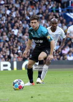 two soccer players in action on the field during a game with fans watching them from the stands