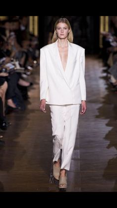 a model walks down the runway in a white suit