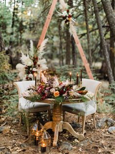 a table with candles and flowers on it in the woods