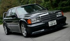 a mercedes benz is parked on the side of the road in front of some trees