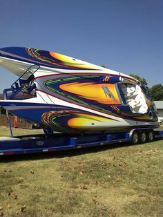 a boat that is sitting on the back of a semi - trailer in a field