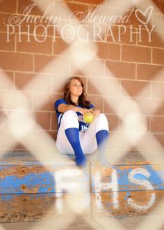 a woman sitting on top of a wooden bench holding a baseball ball and wearing blue socks