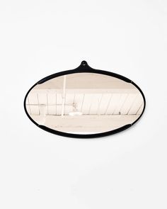 an oval mirror hanging from the side of a wall in front of a white background