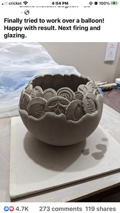 a clay bowl sitting on top of a table next to a sheet of white paper