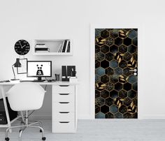 a desk with a computer and a clock on it next to a wallpapered door