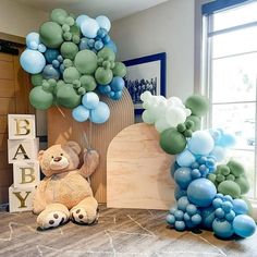 a teddy bear sitting on the floor next to balloons