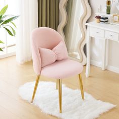 a pink chair with a bow on it in front of a mirror and white rug