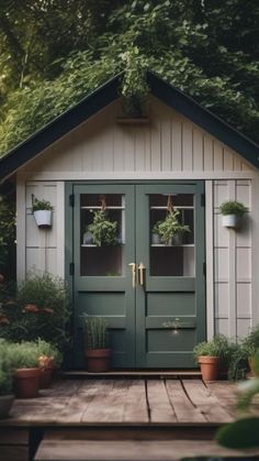 a small shed with potted plants on the front and side windows, along with two doors