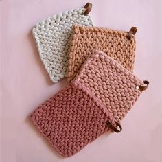 three crocheted pouches sitting on top of each other in pink and white