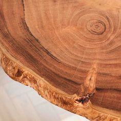 a close up view of a wooden table with rings in the wood and white tile flooring