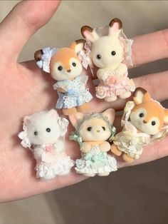 a person's hand holding five tiny animal figurines