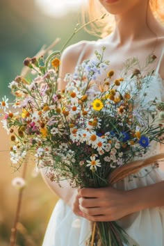 a woman holding a bouquet of wildflowers in her hands