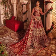 a woman in a red and gold bridal gown standing next to a christmas tree