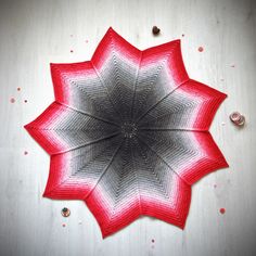 a red and white crocheted flower sitting on top of a table