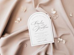 an elegant wedding suite is laid out on top of a satin fabric, with the bride's name printed on it