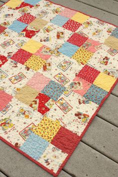 a multicolored patchwork quilt laying on a wooden floor next to a deck