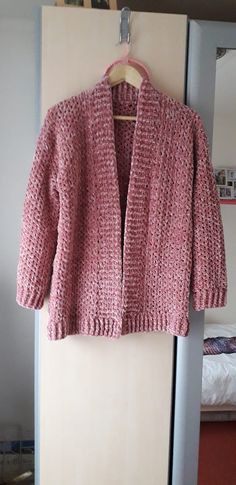 a pink knitted jacket hanging on a wall