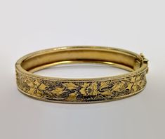 I love this bracelet both in style and condition! This is a Victorian Revival, hinged bangle from the. 1930's - 40's. It is 12K gold filled in wonderful. This has a beautiful etched and textured pattern to it. It features a floral pattern.  The background has a texture to make the flower stand out. It features a slide clasp is in perfect working order with an attached safety latch for extra protection. Beautiful piece on it's own or stack it with more for a statement look. Condition: Very good vintage condition, vintage patina - Only spot that might have wear is right at the clasp, but that might be tarnish; condition consistent with age Measurements: 0.43" or 10.71 mm wide; inside measurement 7" around Weight: 17.2 grams Markings: 1/20 12KTGF and what looks like 3 initials that I cannot m Victorian Hinged Bangle Bracelets, Vintage Yellow Gold Hinged Cuff Bracelet, Ornate Hinged Bangle Bracelets, Ornate Hinged Bangle Bracelet, Victorian Hinged Cuff Bangle Bracelet, Vintage Hinged Gold Bracelet, Vintage Etched Gold Bangle Bracelet, Victorian Hinged Cuff Bracelet, Vintage Hinged Cuff Bracelet