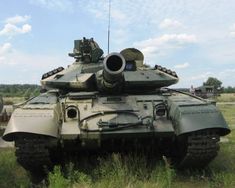 an army tank sitting on top of a grass covered field next to another vehicle in the background