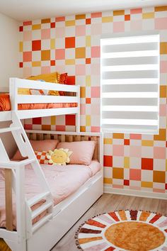 a bedroom with two bunk beds and a rug in front of the window, on top of the floor