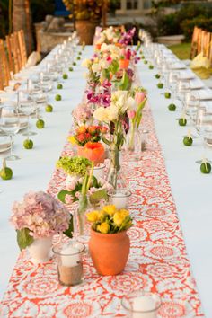 a long table is set up with flowers and candles for an outdoor dinner party or reception