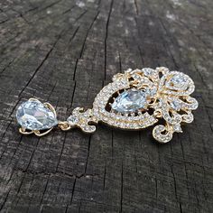 An elegant drop brooch or flat back embellishment in gold tone alloy metal. This is studded with clear crystal rhinestones and glass focal stones. Jointed in two places, this has a bit of motion. Perfect for a flapper headband, sash, or cascading bouquet. It measures 3.75 inches (@ 9.5 cm) long by 2 inches (@ 5 cm) wide. The back is slightly concave and has spaces between the metal so it can be sewn on. It can be ordered without the pin as a flatback embellishment or with a pin to wire into broo Gold Crystal Brooches With Bling, Gold Brooch Jewelry For Wedding, Gold Wedding Brooch Jewelry, Gold Wedding Jewelry With Brooch, Gold Crystal Jeweled Brooches, Gold Crystal Brooches For Formal Occasions, Gold Jeweled Brooches For Wedding, Elegant Gold Jeweled Brooches, Gold Crystal Brooch Jewelry