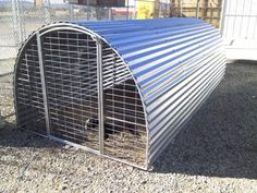 a large metal animal cage sitting on top of gravel