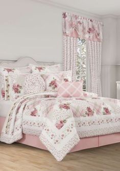 a bed with pink and white comforters in a bedroom next to a window,