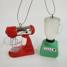 two toy blenders sitting next to each other on a white surface with one red and the other green