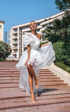 a woman in a white dress is walking down some steps