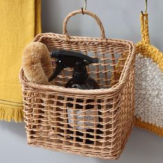 a pair of scissors in a basket next to a yellow towel on a wall with hooks