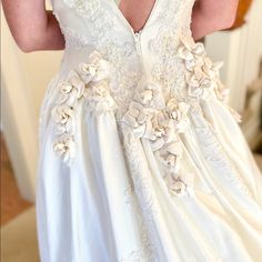 a woman wearing a white dress with flowers on the front and back, is taking a selfie