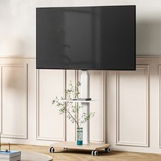 a flat screen tv mounted to the side of a wall next to a table with a vase on it