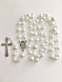 Handmade rosary was made with silver metal wire, 6mm white and 8mm slightly gray faux glass pearls. Rosary center piece has Our Lady on one side and Jesus on the other. Comes in a gift pouch Elegant White Cross Rosary, White Cross Jewelry With Miraculous Medal, Pearl White Rosary With 8mm Beads As Gift, Silver Pearl Rosary With 8mm Beads, White Pearl Rosary As A Gift, White Pearl Rosary As Gift, White Crucifix Rosary With Miraculous Medal, White Spiritual Rosary With Miraculous Medal, Spiritual White Rosary With Miraculous Medal