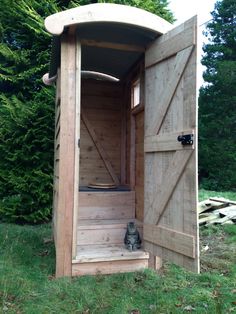 a cat sitting in the doorway of a wooden structure with its door open and stairs leading up to it