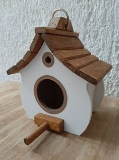 a white birdhouse with a brown roof on a wooden table