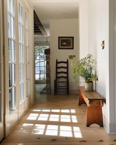 the sun shines through the windows onto an empty hallway with a bench and chair