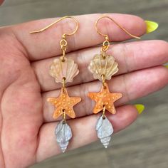 a pair of earrings with shells and starfish charms