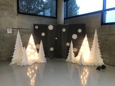 three white christmas trees with snowflakes on them in front of a large window