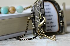 a necklace with an antique key hanging from it's side next to a book