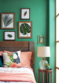 a bedroom with green walls and pictures on the wall above the bed, along with a wooden headboard